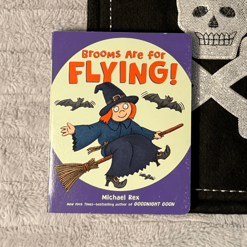 Brooms Are for Flying board book cover with a cartoon witch on a broom with bats behind her