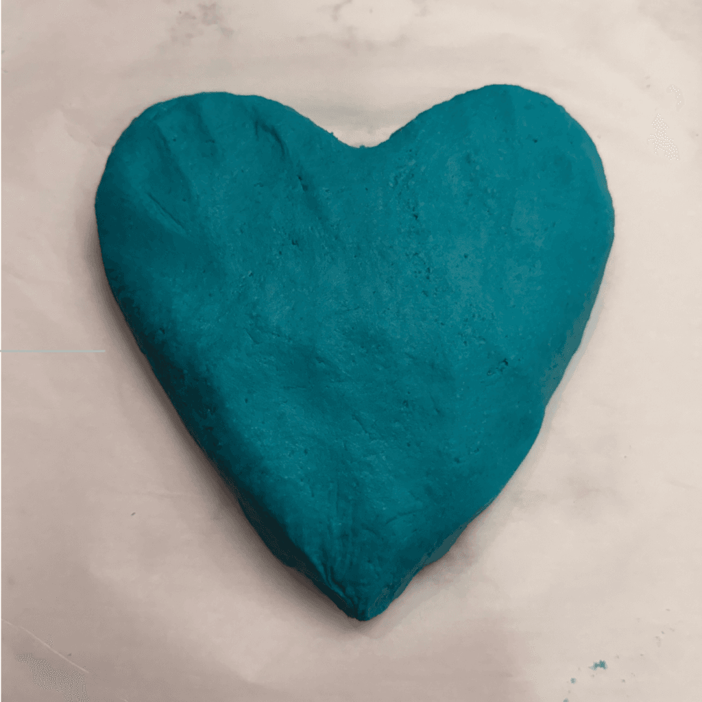 No-cook play dough recipe: close-up of smooth, kneaded teal play dough shaped like a heart