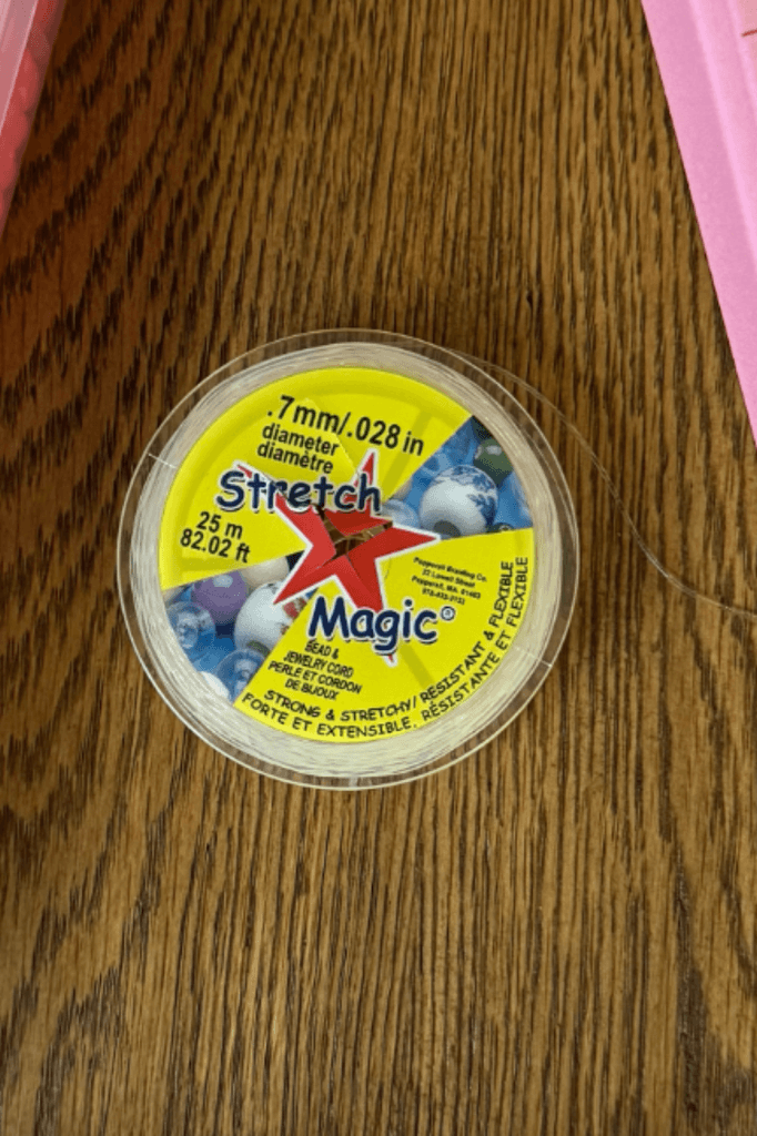 Spool of Stretch Magic elastic beading cord next to a finished kids' beaded bracelet
