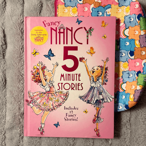 Fancy Nancy 5-Minute Stories hardcover book with a pink cover on a Care Bears blanket